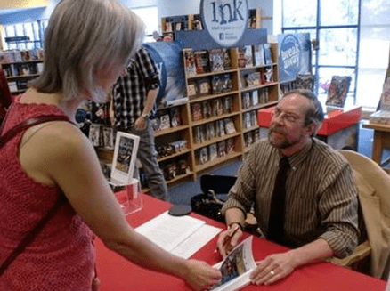 Man autographing book for woman
