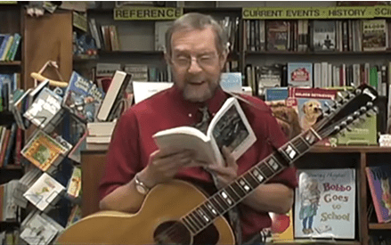 Man reading book with guitar in bookstore