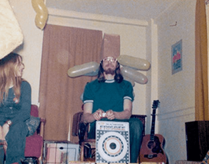 Room with guitar, person wearing balloon hat