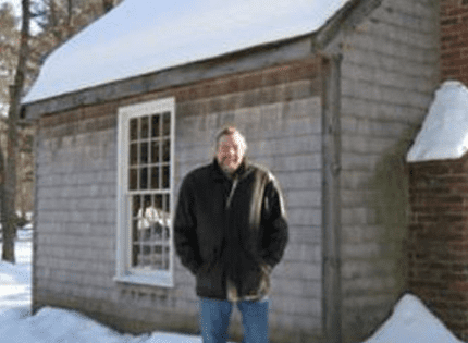 Person in winter coat by cabin